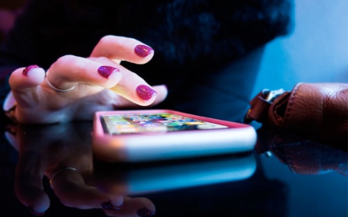 Girl scrolling through her mobile phone looking for apps.