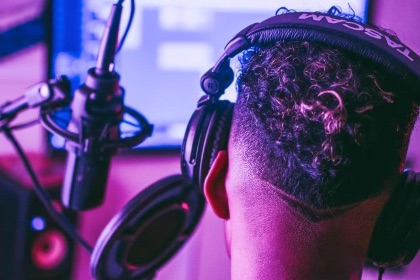 Male facing computer and microphone playing a computer game.